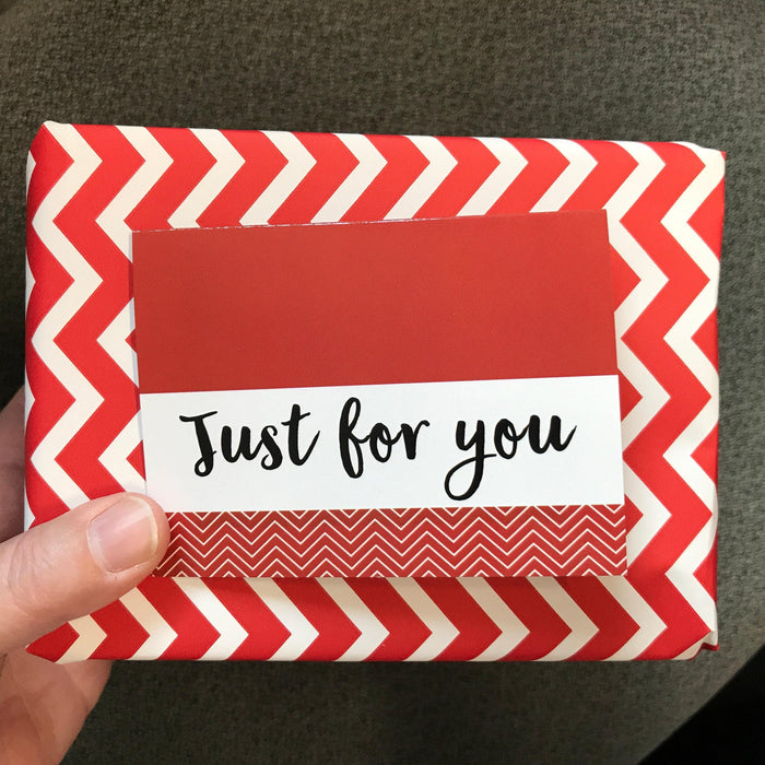 Red chevron gift card envelope with 'Just for you' label, held in a hand